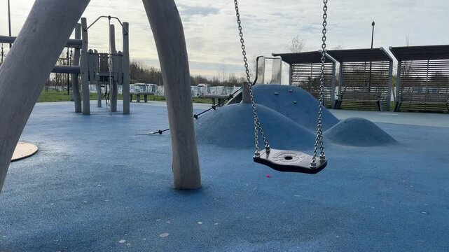 Empty swing set on a modern playground, childhood fun concept, public park recreation, safe outdoor play.
