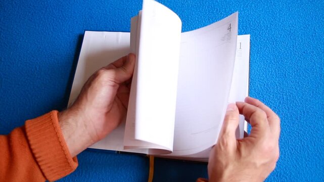Hojeando agenda de notas y diario con p&aacute;ginas de papel y anotaci&oacute;n a mano en cuaderno libro
