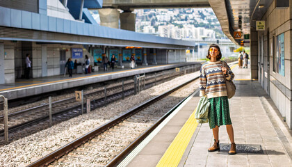Naklejka premium girl looking at watch and waiting for train. girl standing at train station waiting for train.