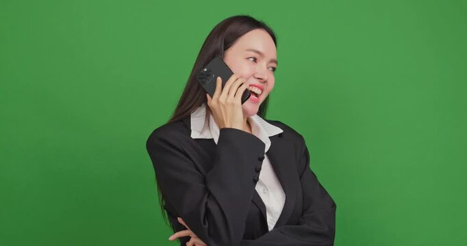 Happy businesswoman talking on a smartphone and laughing on a green screen background.