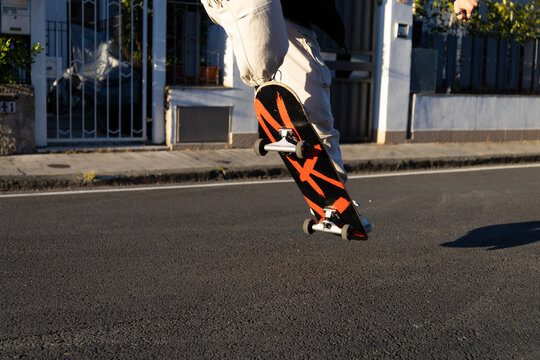 Skater che esegue un ollie su strada su asfalto al tramonto