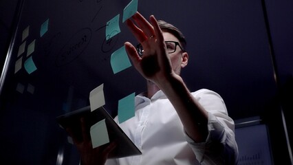 Man in eyeglasses organizing thoughts and ideas for business optimization on a clear glass board....
