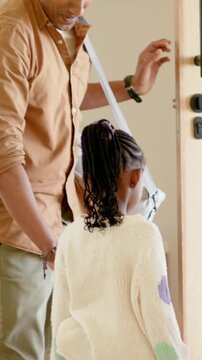 Vertical video: Arriving dad with gray bag at keypad entry, opening door, guiding daughter in dots