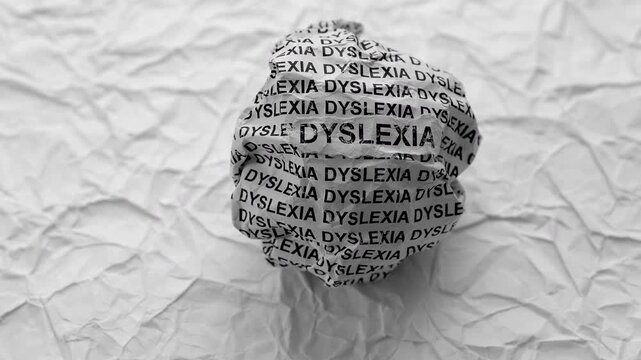 Crumpled paper ball with words Dyslexia on a crumpled white paper background.