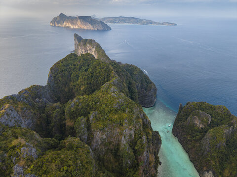 Aerial view of Phi Phi Islands featuring lush limestone cliffs, turquoise waters of a narrow bay, and boats anchored near the shore in Mueang Krabi District, Krabi, Thailand.
