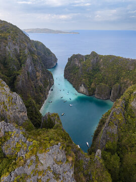 Aerial view of the Phi Phi Islands featuring a turquoise lagoon surrounded by steep limestone cliffs and small boats in Mueang Krabi District, Krabi, Thailand.