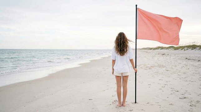 Woman holding orange flag pole on sandy beach