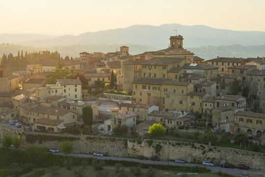 Aerial view of the historic hilltop town of Montefalco with its ancient stone buildings, defensive walls, and prominent clock tower under a warm golden sunset light Montefalco, Umbria, Italy.
