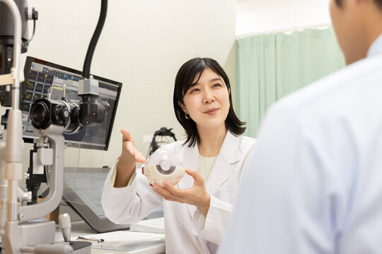 眼科医が眼球模型で説明する診察シーン・視力と目の健康カウンセリング(モニターはテスト画面のはめ込み)