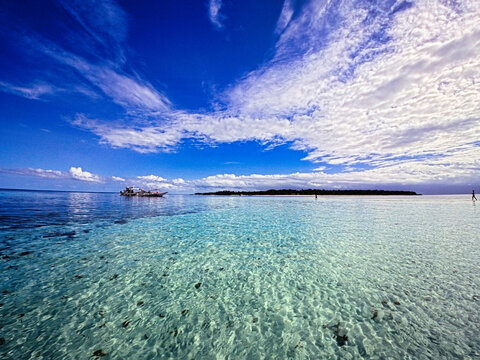 A breathtaking wide-angle view of Starfish Sandbar in Balabac, Palawan, Philippines. Crystal-clear shallow waters stretch across pristine white sand, forming delicate ripple patterns beneath the surfa