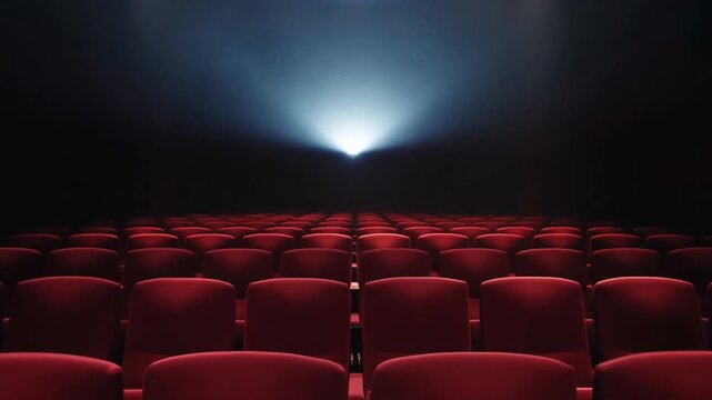 Static shot of empty theater rows with projector beam shining toward screen in dark auditorium