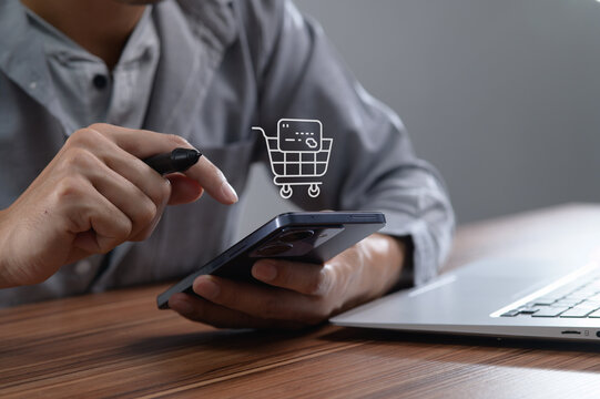 Man Using Smartphone for Online Shopping with Laptop on Desk