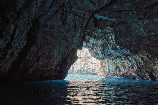 Dramatic view from inside a dark sea grotto looking out at turqu