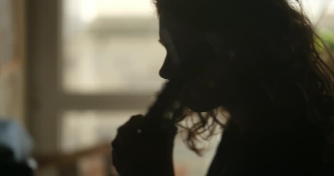 cinematic vintage video showing a romantic profile of a teenage girl playing guitar in backlight, with a piano and sheet music in a home interior. moment of musical practice in a cozy home environment
