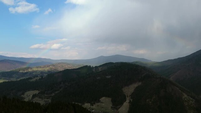 Aerial View of Mountain Range with Forest and Subtle Rainbow