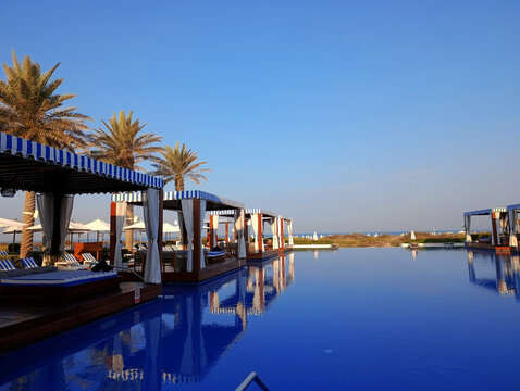Striped cabana sunbeds in the shaded area by the swimming pool by the sea on Saadiyat island in Abu Dhabi