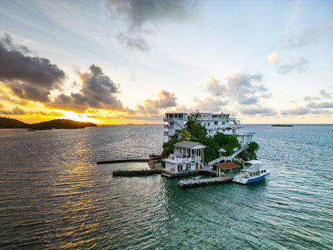 Aerial view of the Villa on Dunbar Rock resort built on a small rocky cay surrounded by turquoise Caribbean waters at sunset Guanaja, Bay Islands Department, Honduras.