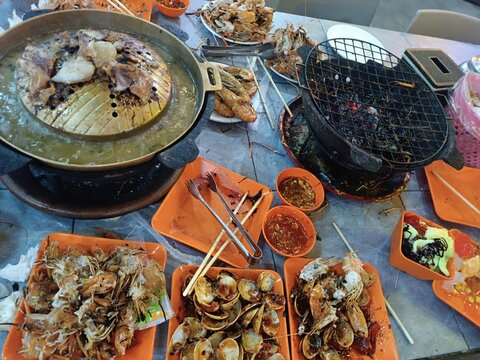Finished Thai BBQ Moo Krata dinner with used grill and empty shells on plate.