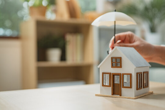 Home insurance concept with house model protected by umbrella symbolizing risk coverage, property protection, and financial security, representing homeowner safety, insurance policy planning.