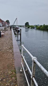 Cobblestone Harbor Quay Along Ribe River with Moored Boats, Ribe, Denmark