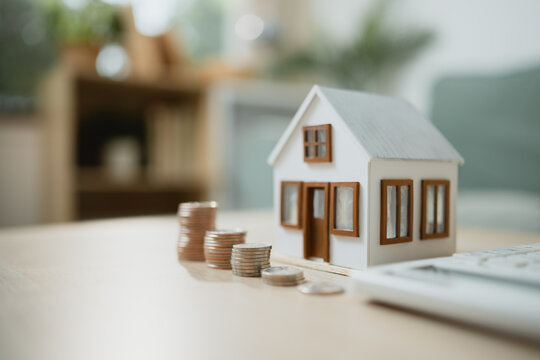Small house model with stacked coins representing real estate investment, mortgage planning, and financial growth, symbolizing property value, savings, and long term wealth building strategy.