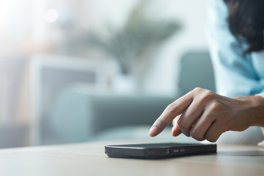 Person using smartphone with finger tapping on screen in a modern home setting, representing mobile technology, digital communication, and everyday online interaction.