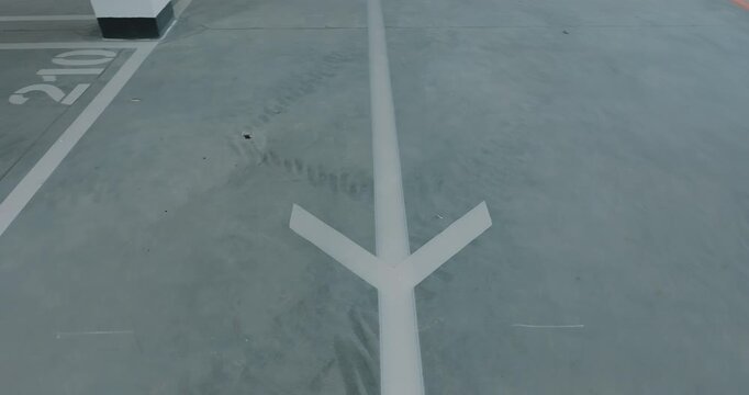 Directional arrow marking on concrete floor with parking space lines close up