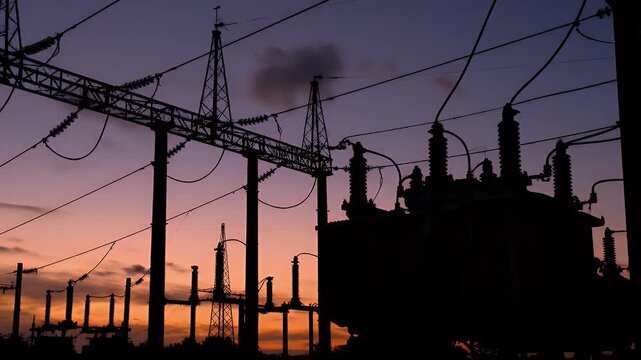 Silhouette of Electrical Substation at Dusk With Power Lines and Structures Against Orange Purple Sky Ideal for