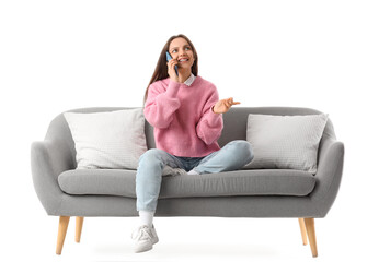 Obraz premium Young woman talking by mobile phone on grey couch against white background