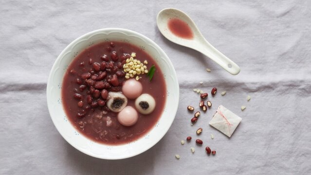 Sweet red bean soup with tangyuan and barley on grey background