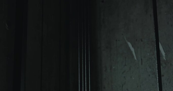 Steel elevator cables against concrete wall close up
