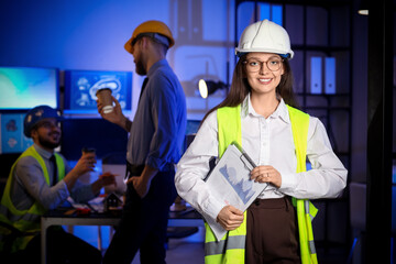 Fototapeta premium Female engineer with clipboard in office at night