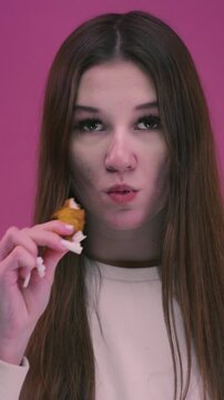 Woman eating a fried chicken wing from fast food. Teen girl bites unhealthy junk. Crispy chicken pieces, takeaway food, casual dining moment. Young female have a crispy meat.