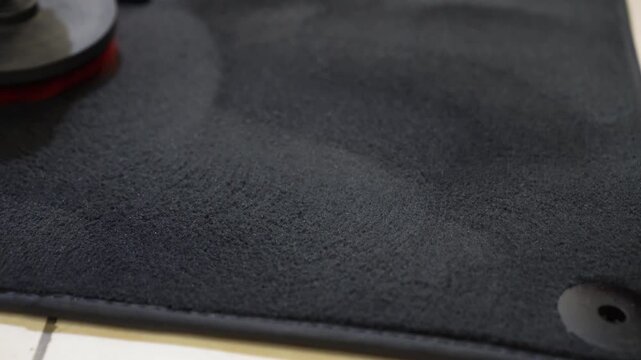Brush cleaning off dust from the car interior details, control panel of the dashboard. The detailing master cleans the car interior with a hot steam cleaner, brush. Carpet cleaning with a round brush.