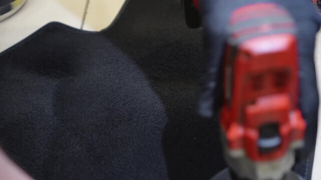 Brush cleaning off dust from the car interior details, control panel of the dashboard. The detailing master cleans the car interior with a hot steam cleaner, brush. Carpet cleaning with a round brush.