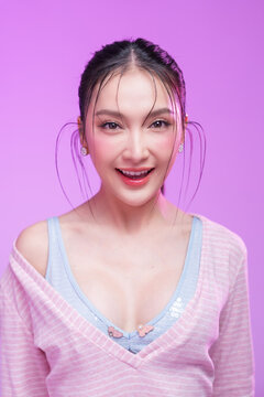 Beautiful young Asian woman with glowing skin and trendy wet hair look posing against a pastel pink background; elegant fashion portrait showcasing skincare, facial treatment, and Gen Z aesthetic.