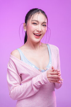 Beautiful young Asian woman with glowing skin and trendy wet hair look posing against a pastel pink background; elegant fashion portrait showcasing skincare, facial treatment, and Gen Z aesthetic.