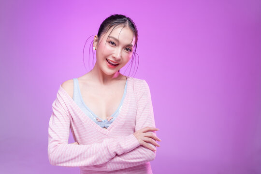 Beautiful young Asian woman with glowing skin and trendy wet hair look posing against a pastel pink background; elegant fashion portrait showcasing skincare, facial treatment, and Gen Z aesthetic.