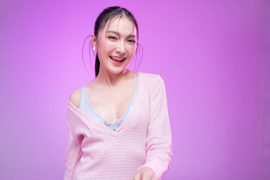 Beautiful young Asian woman with glowing skin and trendy wet hair look posing against a pastel pink background; elegant fashion portrait showcasing skincare, facial treatment, and Gen Z aesthetic.