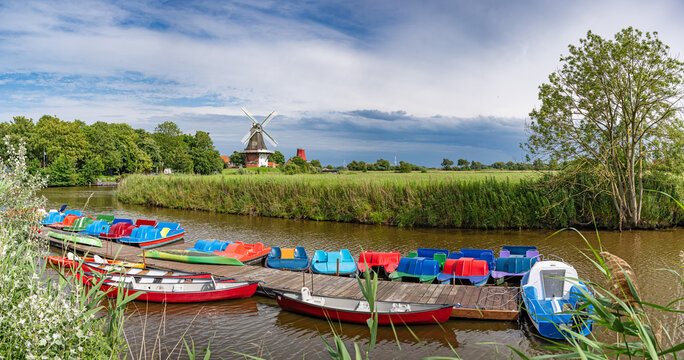 Greetsiel, Ostfriesland, Niedersachsen, Deutschland - Bunte Boote der Bootsverleihstation am Greetsieler Siel vor den Greetsieler Zwillingsm&uuml;hlen