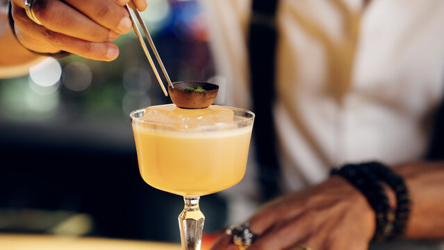 Bartender carefully placing an artistic garnish on a professionally mixed cocktail, highlighting craft and luxury beverage service