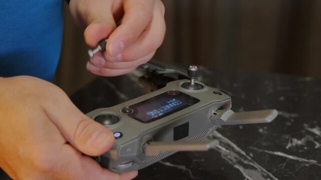 male hands attaching control sticks to drone remote controller close-up, tightening joysticks and preparing device for flight control, practical setup process for piloting and equipment use