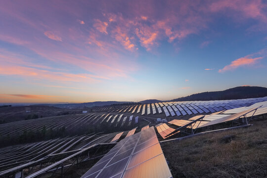 Aerial View of Solar Farm on Rolling Hills at Sunrise