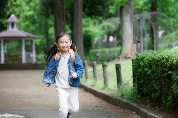 Fototapeta premium ランドセルで走る元気な小学生の全身ポートレート小学生低学年の登校や下校などの通学や成長ののイメージ