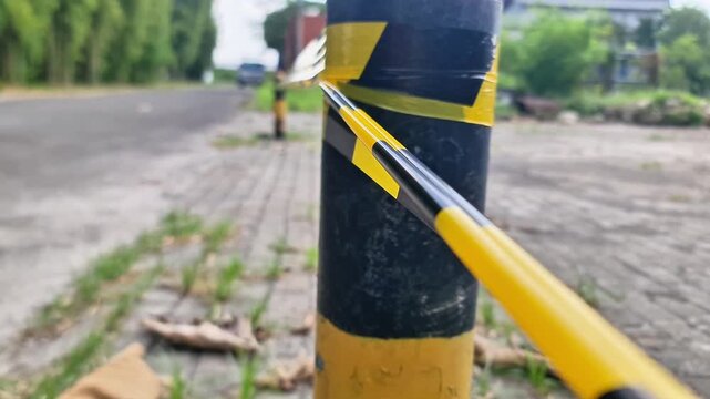 Close-Up of Yellow and Black Hazard Warning Tape on Safety Bollard Securing Restricted Area