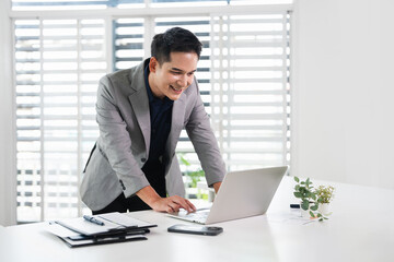 Fototapeta premium Happy professional business man company employee, young busy smiling male businessman entrepreneur or worker using laptop computer technology working at corporate office desk.