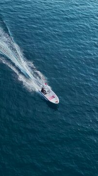 Vertical top view of speedboat cutting through blue ocean surface