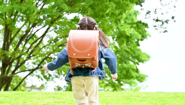ランドセルで走る元気な小学生の全身ポートレート小学生低学年の登校や下校などの通学や成長ののイメージ　顔無しの後ろ姿の動画　スローモーション