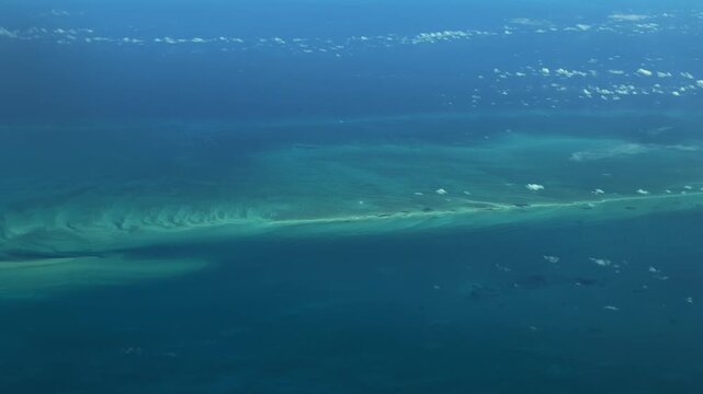 flying across Atlantic Ocean with long strip of turquoise water surface and a small atolls in The Bahamas, located in the Caribbean Sea - 4k aerial video footage 