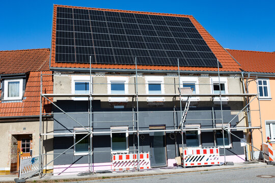 Energetische Sanierung, Zweifamilien-Wohnhaus; Au&szlig;enansicht Mehrfamilienhaus mit R&uuml;stung, Solaranlage (Fhotovoltaik) auf Wohnhausdach und D&auml;mmung Fassade